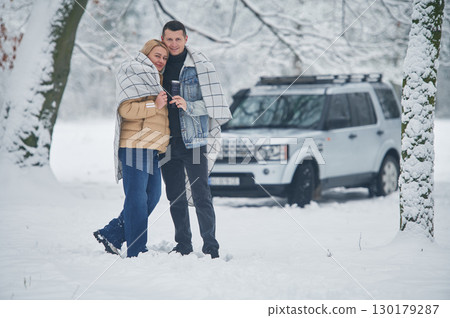 Embracing each other. Beautiful couple standing near the car in the winter forest Embracing each other. Beautiful couple standing near the car in the winter forest 130179287