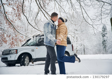 Conception of love. Beautiful couple standing near the car in the winter forest Conception of love. Beautiful couple standing near the car in the winter forest 130179297