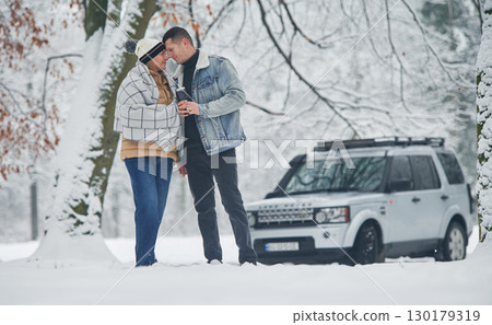 Beautiful couple standing near the car in the winter forest 130179319