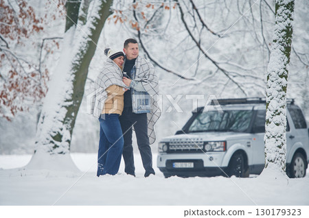 Beautiful nature. Couple is standing near the car in the winter forest Beautiful nature. Couple is standing near the car in the winter forest 130179323