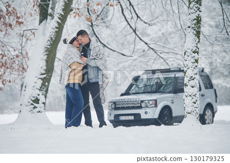 Beautiful nature. Couple is standing near the car in the winter forest Beautiful nature. Couple is standing near the car in the winter forest 130179325