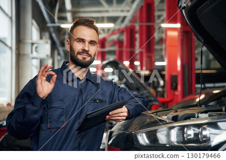 Using tablet. Car repairman is in the garage with automobile Using tablet. Car repairman is in the garage with automobile 130179466