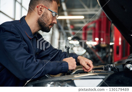 Hood is opened, fixing. Car repairman is in the garage with automobile Hood is opened, fixing. Car repairman is in the garage with automobile 130179489