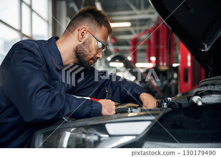 Car repairman is in the garage with automobile Car repairman is in the garage with automobile 130179490