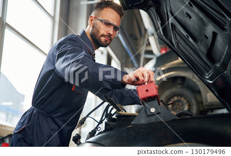 Car repairman is in the garage with automobile 130179496