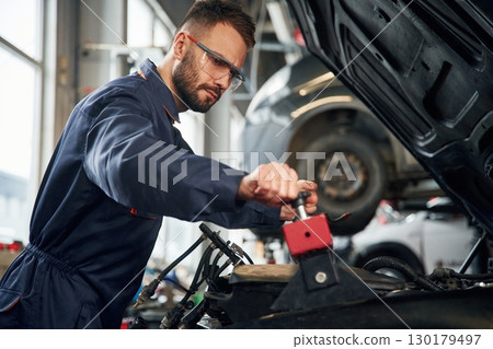 Car repairman is in the garage with automobile 130179497