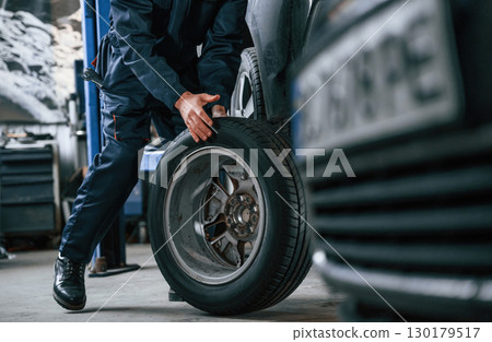 Close up view of man that is moving tire of the car Close up view of man that is moving tire of the car 130179517
