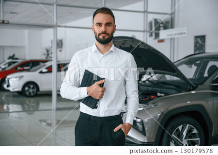 Portrait of beautiful man. Worker in formal clothes is in the auto salon 130179578