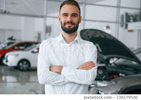 Portrait of beautiful man. Worker in formal clothes is in the auto salon Portrait of beautiful man. Worker in formal clothes is in the auto salon 130179580