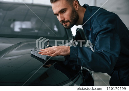 Polishing the vehicle. Car repairman is in the garage with automobile 130179599