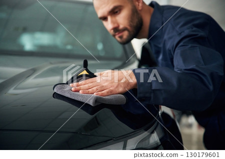 Process of polishing the surface with cloth. Car repairman is in the garage with automobile Process of polishing the surface with cloth. Car repairman is in the garage with automobile 130179601