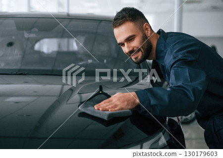 Process of polishing the surface with cloth. Car repairman is in the garage with automobile 130179603