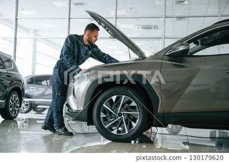 Fixing the vehicle. Side view. Car repairman is in the garage with automobile 130179620