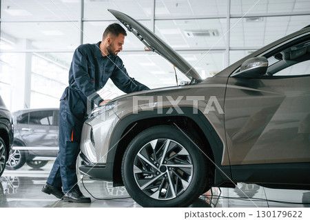 Fixing the vehicle. Side view. Car repairman is in the garage with automobile 130179622