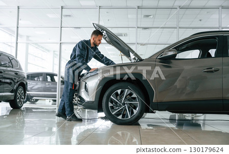 Fixing the vehicle. Side view. Car repairman is in the garage with automobile 130179624
