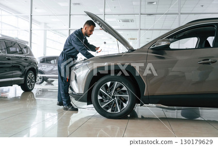 Focused on fixing the vehicle. Car repairman is in the garage with automobile Focused on fixing the vehicle. Car repairman is in the garage with automobile 130179629