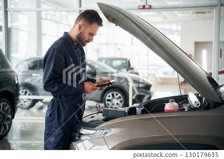 View from the side. Car repairman is in the garage with automobile 130179635