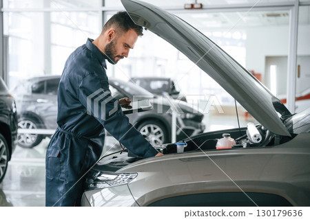 View from the side. Car repairman is in the garage with automobile 130179636