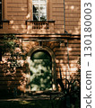 Soft sunlight penetrating leafy branches casting intricate shadows across weathered stone archway, highlighting architectural details with ethereal light patterns. Sunlight creates dappled shadows 130180003
