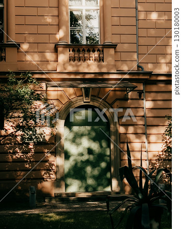 Soft sunlight penetrating leafy branches casting intricate shadows across weathered stone archway, highlighting architectural details with ethereal light patterns. Sunlight creates dappled shadows 130180003