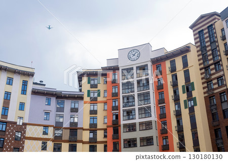 multi-level courtyard of a modern apartment building with a clock on the facade 130180130