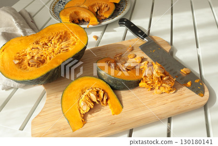 Pieces, slices of pumpkin on wooden board with knife. Farm products and healthy eating. Kitchen and home cooking. Pieces, slices of pumpkin on wooden board with knife. Farm products and healthy eating. Kitchen and home cooking. 130180141