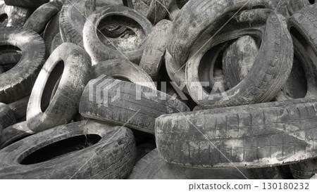 Piles of discarded rubber tires are visible, illustrating the severe pollution and ecological problems caused by improper waste management practices. 130180232
