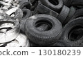 Piles of discarded rubber tires accumulate in a neglected area, highlighting the pressing ecological problems related to waste management and pollution in urban environments. 130180239