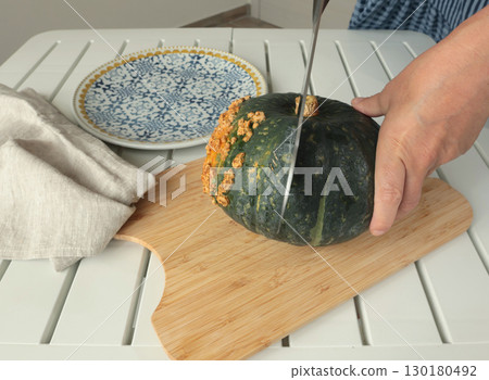 Anonymous cut pumpkin on wooden board. Farm products and healthy eating. Seasonal food, vegetarian dish. 130180492