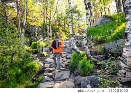 A man hiking on a stone stairway to the top of a cliff of the beautiful Lysefjord on a sunny day. The beautiful wild nature of Norway A man hiking on a stone stairway to the top of a cliff of the beautiful Lysefjord on a sunny day. The beautiful wild nature of Norway 130181060