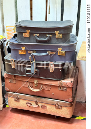 A tall stack of vintage leather and hard-shell suitcases arranged in a flea market interior. Flea market, retro travel, secondhand finds, heritage storage 130181315