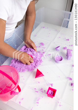 Child playing with purple kinetic sand engaging in creative playtime fun Child playing with purple kinetic sand engaging in creative playtime fun 130181490