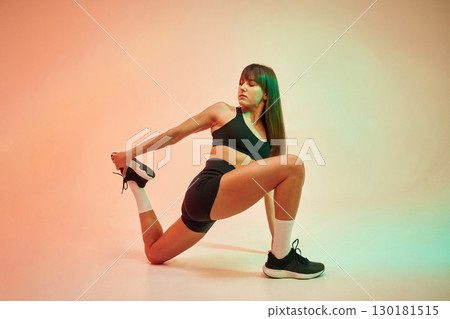 Stretching exercises. Young woman in fitness clothes is in the studio 130181515