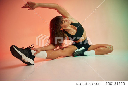 Sitting on the floor. Young woman in fitness clothes is in the studio 130181523