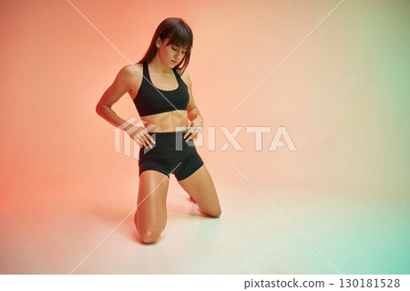 On the knees. Young woman in fitness clothes is in the studio 130181528