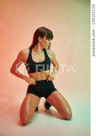 On the knees. Young woman in fitness clothes is in the studio 130181529