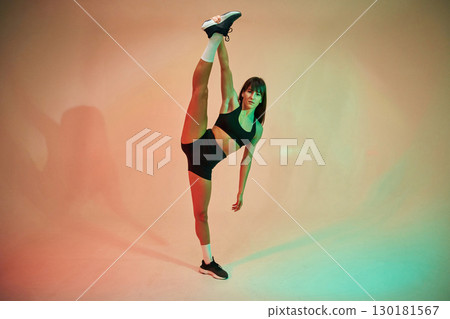 Standing and doing exercises. Young woman in fitness clothes is in the studio Standing and doing exercises. Young woman in fitness clothes is in the studio 130181567