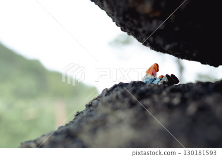 Sokolec Castle, ruins. A plastic dwarf figure lies under a rock, observing the peak opposite. funny trend in Polish mountains 130181593