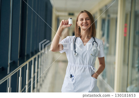 Little bottle with pills in hands. Female doctor in white coat is in the hall Little bottle with pills in hands. Female doctor in white coat is in the hall 130181653