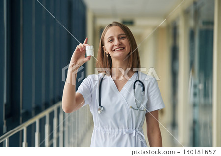 Little bottle with pills in hands. Female doctor in white coat is in the hall 130181657