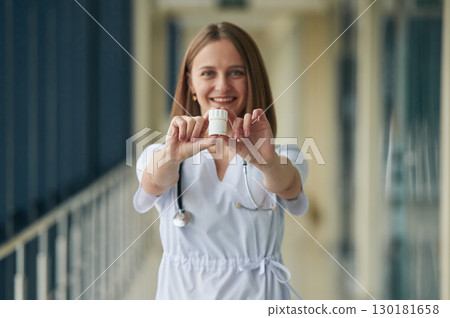 Holding prescription medicals. Female doctor in white coat is in the hall 130181658