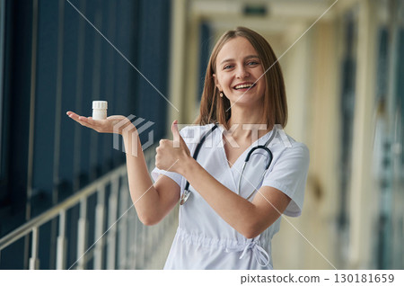 Holding prescription medicals. Female doctor in white coat is in the hall 130181659