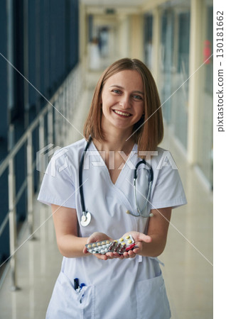 Bunch of pills in hands. Female doctor in white coat is in the hall 130181662