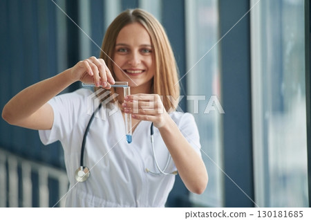 Test tubes with liquid in them. Female doctor in white coat is in the hall 130181685