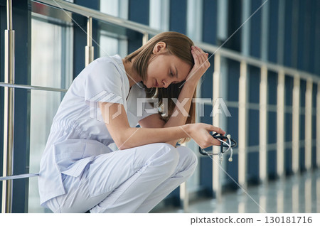 Tired, feeling bad, exhausted. Female doctor in white coat is in the hall 130181716