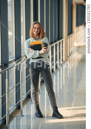 Drink, notepad and tablet in hands. Young woman in airport hall 130181765