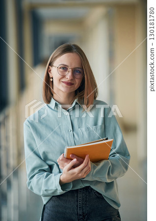 Posing, holding yellow notepad. Young woman in airport hall 130181780