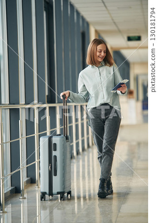 Happy tourist with luggage. Young woman in airport hall Happy tourist with luggage. Young woman in airport hall 130181794