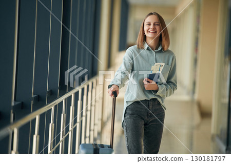 Happy tourist with luggage. Young woman in airport hall 130181797