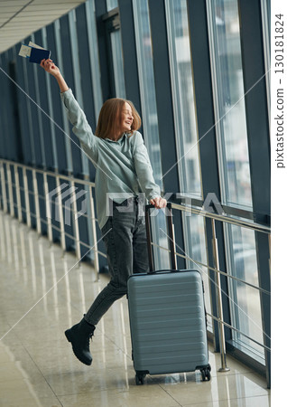 In corridor with tickets and luggage bag. Young woman in airport hall In corridor with tickets and luggage bag. Young woman in airport hall 130181824